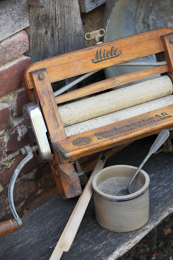 Wringmaschine und Holzasche als traditionelle Hilfsmittel zum Waschen