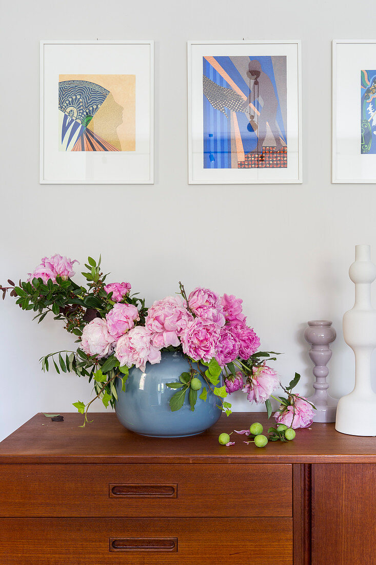 Natural-style arrangement of peonies on sideboard
