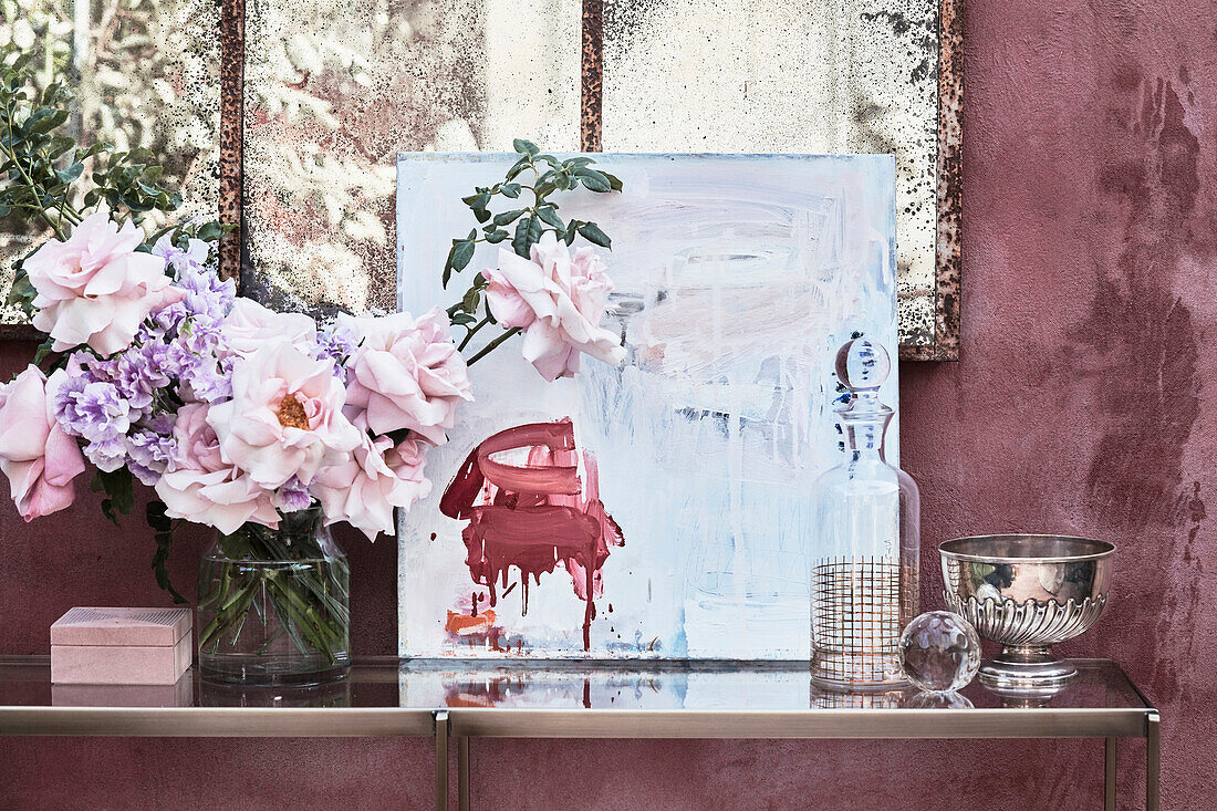 Bouquet of flowers, modern art, glass carafe, and silver bowl on a console table