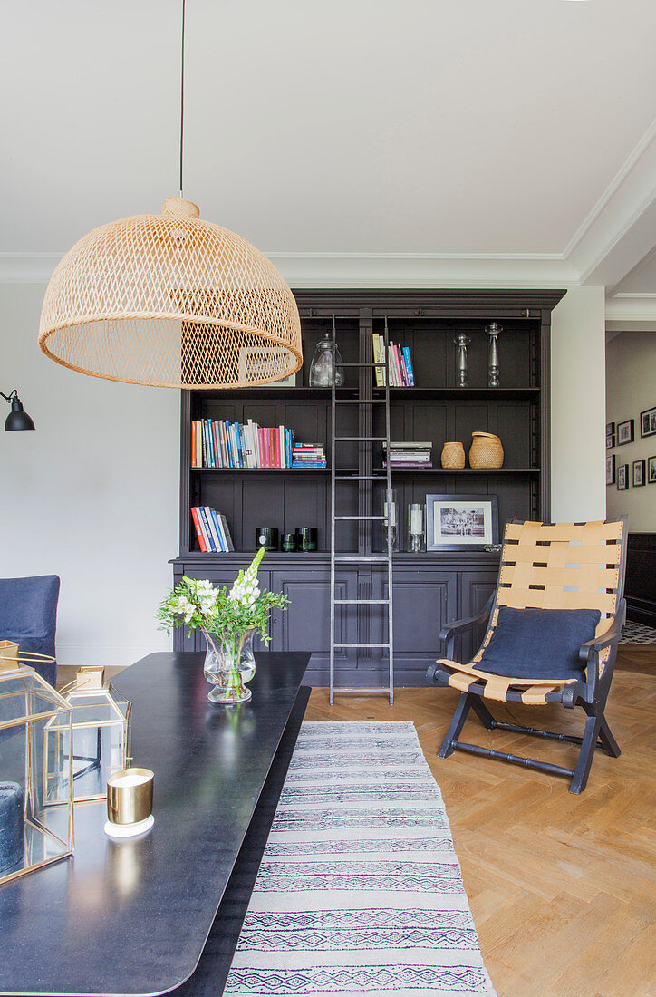 Couchtisch aus Metall, dunkler Bücherschrank mit Bibliotheksleiter und Stuhl im Wohnzimmer mit Fischgrätparkett