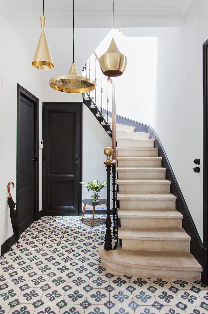 Pendant lamps with golden lampshades in stairwell with cement floor tiles