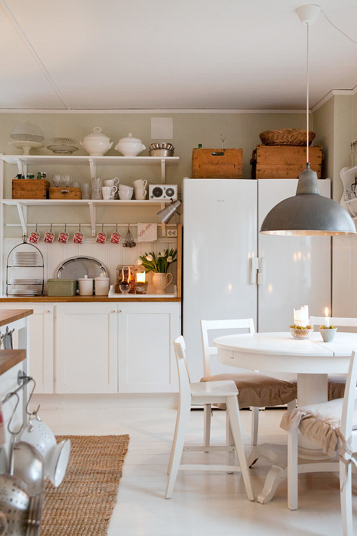 Runder Esstisch mit Stühlen in ländlicher Küche im Weiß