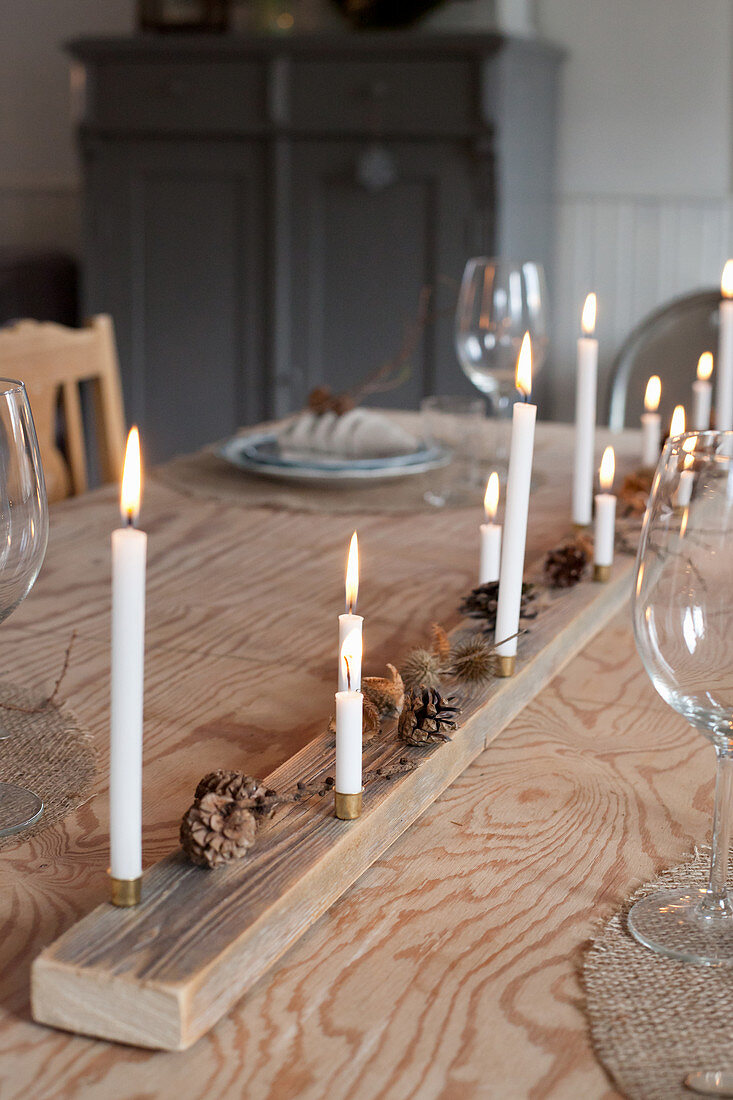 DIY-Weihnachtsdekoration aus Naturmaterial mit Kerzen auf Essstisch