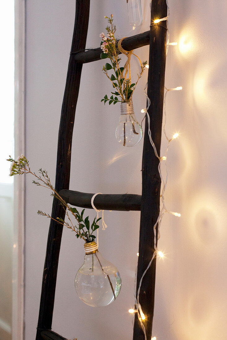 Old light bulbs used as vases and fairy lights hung from ladder