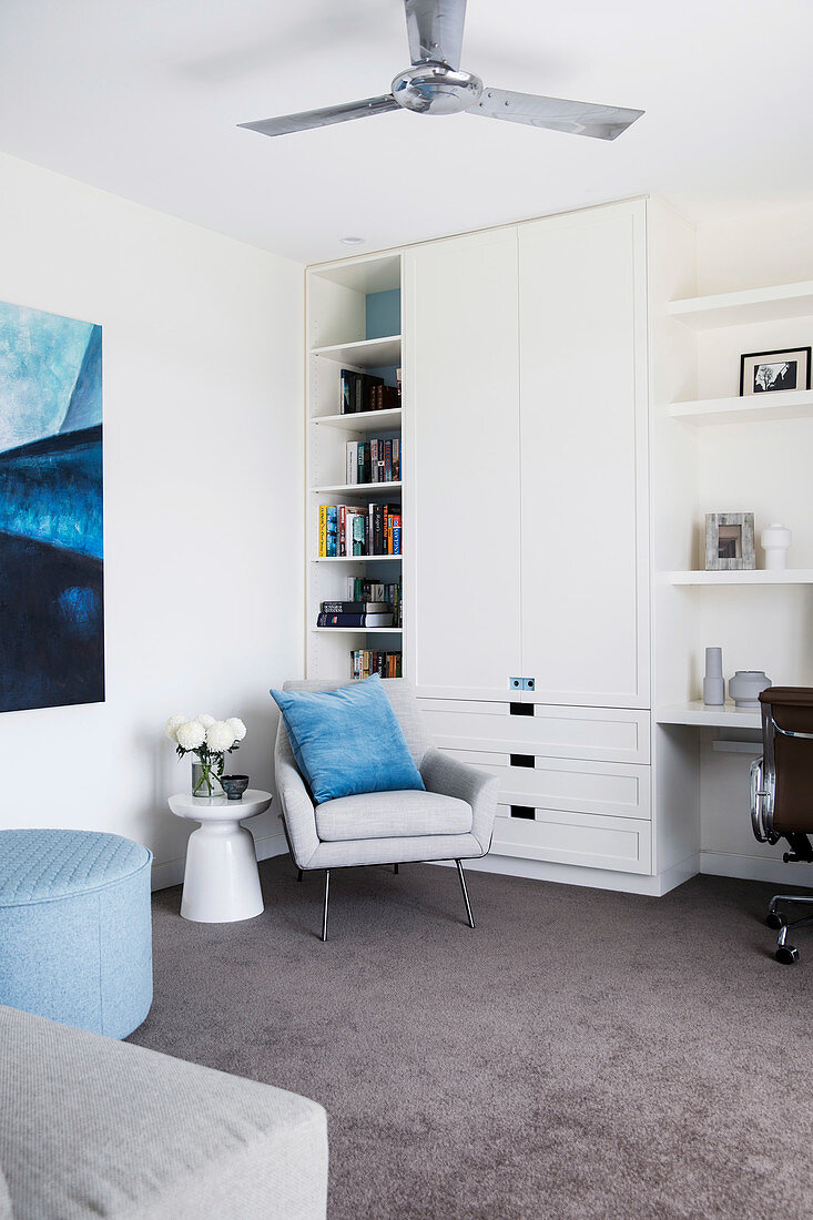 White wall unit with integrated desk, armchair and side table in front