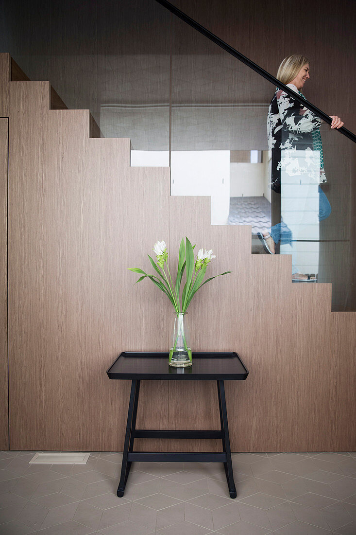 Tabletttisch mit Blumenstrauß vor Treppe mit Geländer aus Glas