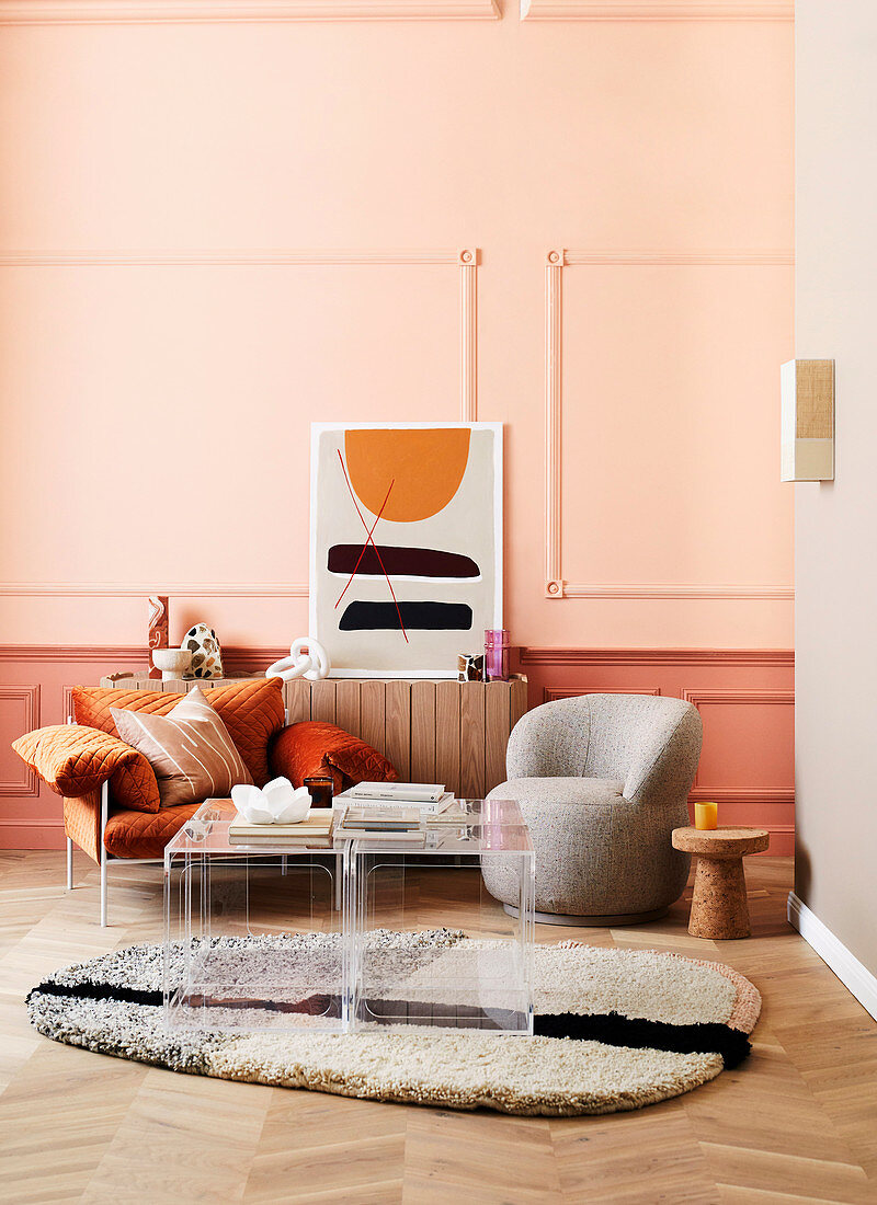 Designersessel und Plexiglas-Tischset im Wohnzimmer vor apricotfarbener Wand