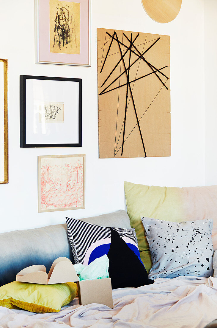 Gerahmte Bilder und DIY-Pinnwand aus Pappe über Sofa mit Kissen