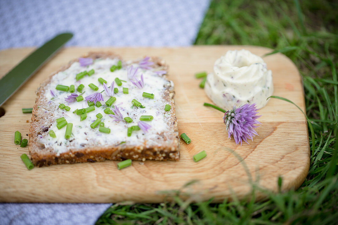 Bread spread with homemade chive-flower butter and sprinkled with chives