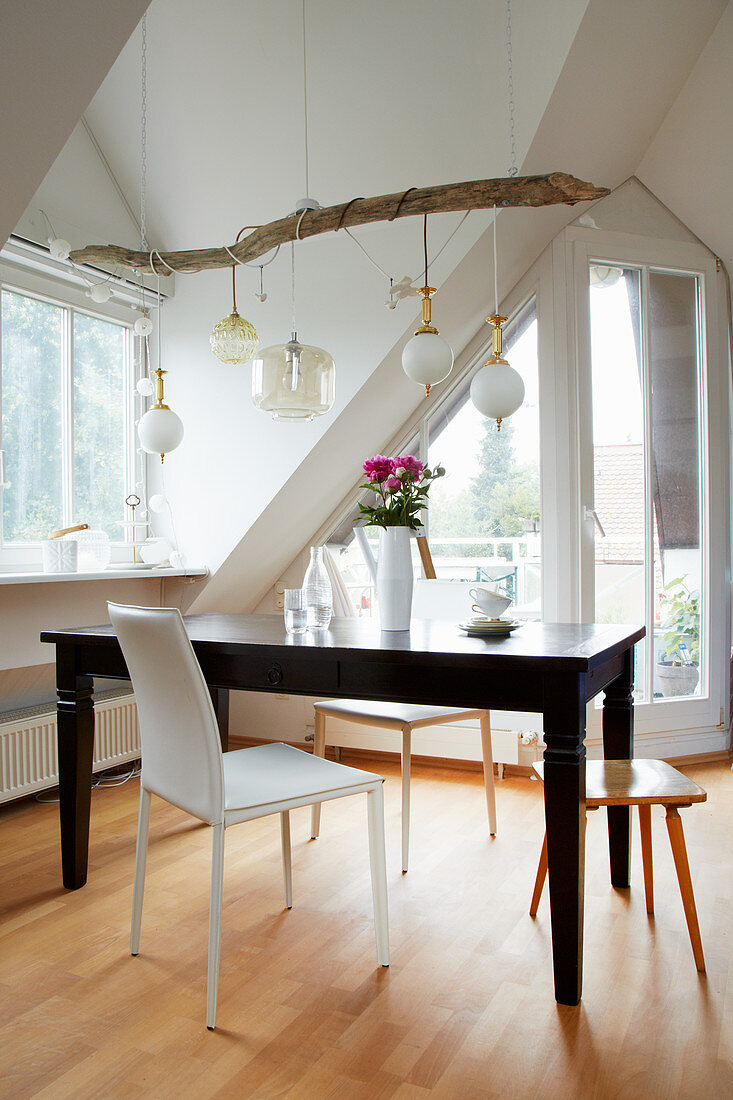 Various pendant lamps with cords wrapped around branch above dining table