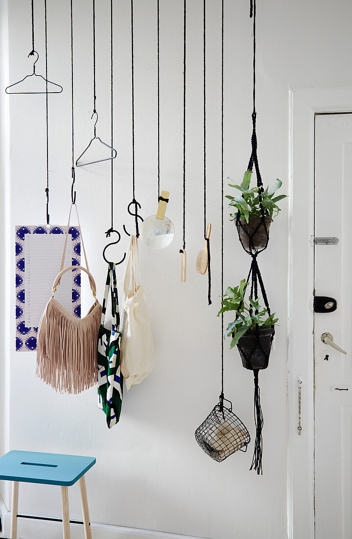 DIY-Garderobe aus schwarzem Seil und Fleischerhaken vor weißer Wand