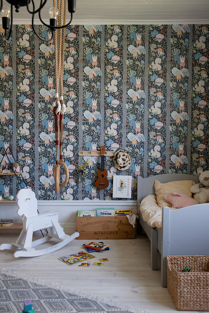 Schaukelpferd, Turnringe und Holzbett im Kinderzimmer mit bunter Tapete