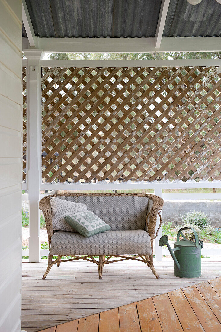 Rattansofa auf der Veranda mit Holzboden und Sichtschutzzaun