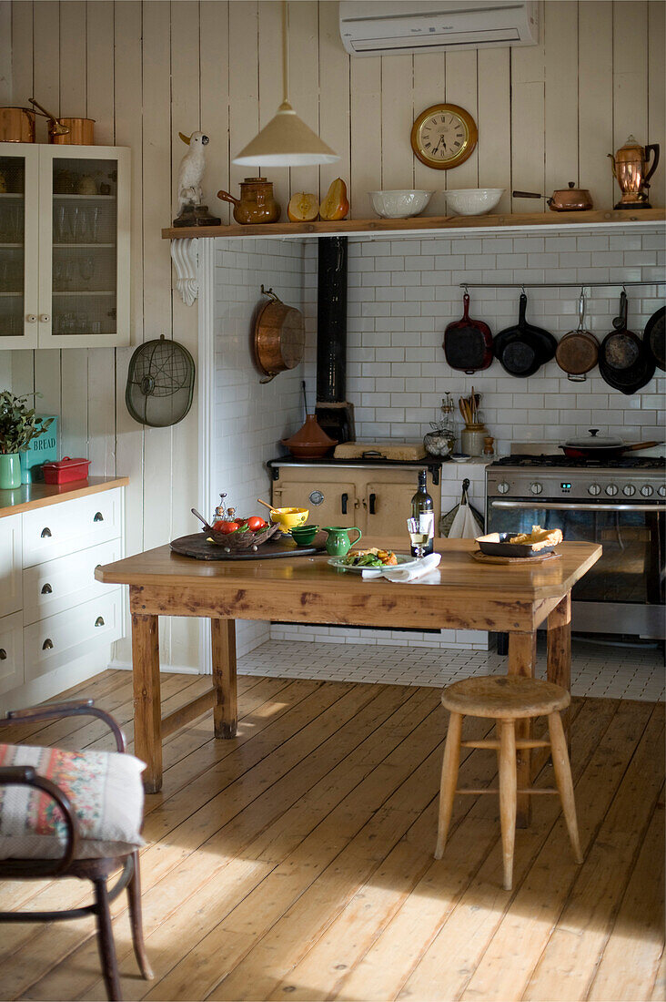 Holztisch in rustikaler Landhausküche mit Holzboden und Küchenofen