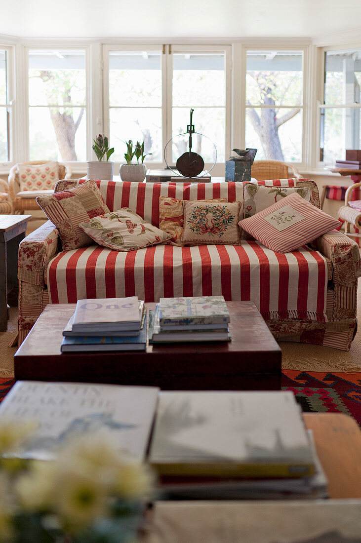 Sofa mit rot-weiß gestreiftem Plaid und geblümten Kissen im Wohnzimmer