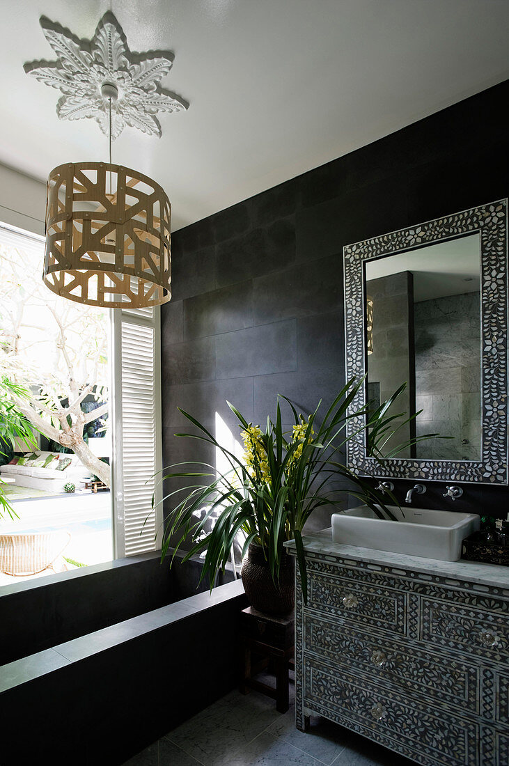 Kommode und Spiegelrahmen mit Perlmutt Intarsien in schwarzem Badezimmer mit Badewanne