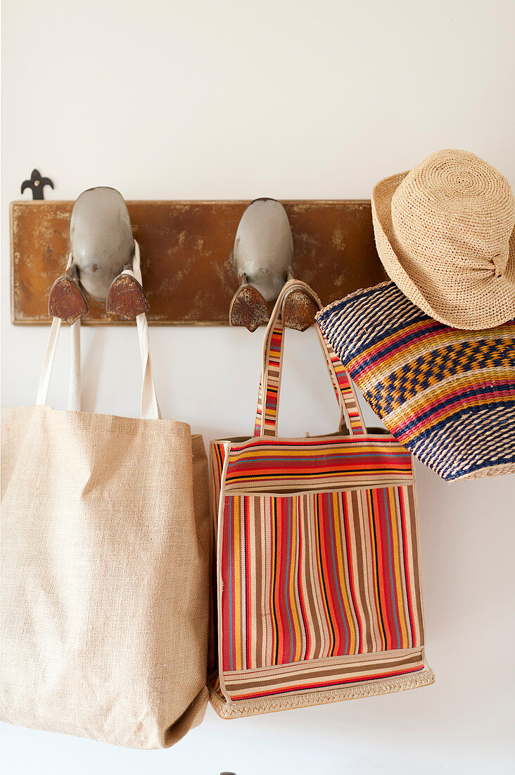 Sommerhut, Korb und Taschen an einer Garderobe mit Entenfüßen