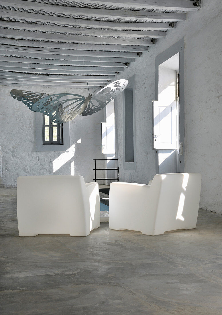 Two white plastic armchairs in traditional Greek house