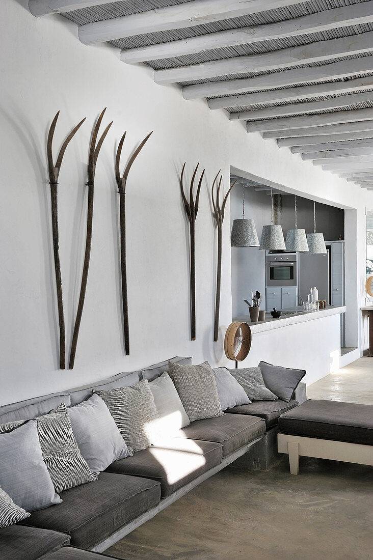 Pitchforks on wall above sofa with scatter cushions in shades of grey