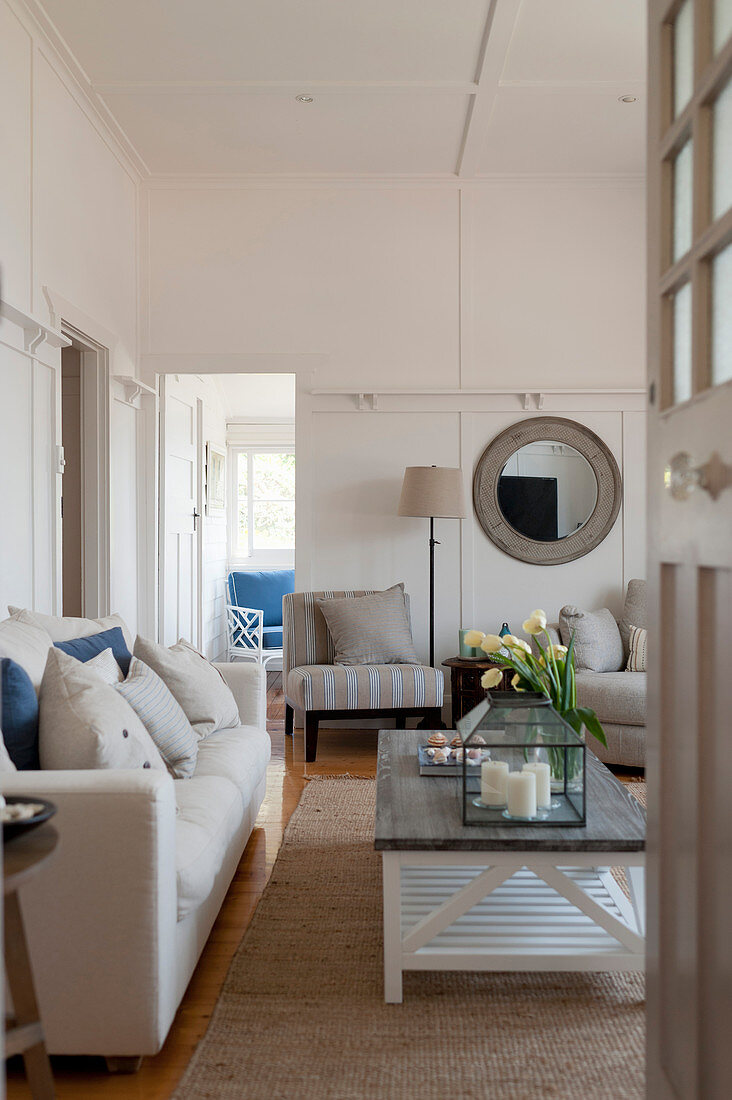 Blick auf Sofa mit Leinenbezug, Couchtisch und Polsterstuhl im Wohnzimmer