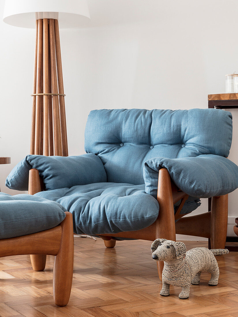Gemütlicher Sessel mit blauer Auflage neben Stehleuchte, im Vordergrund Stoffhund
