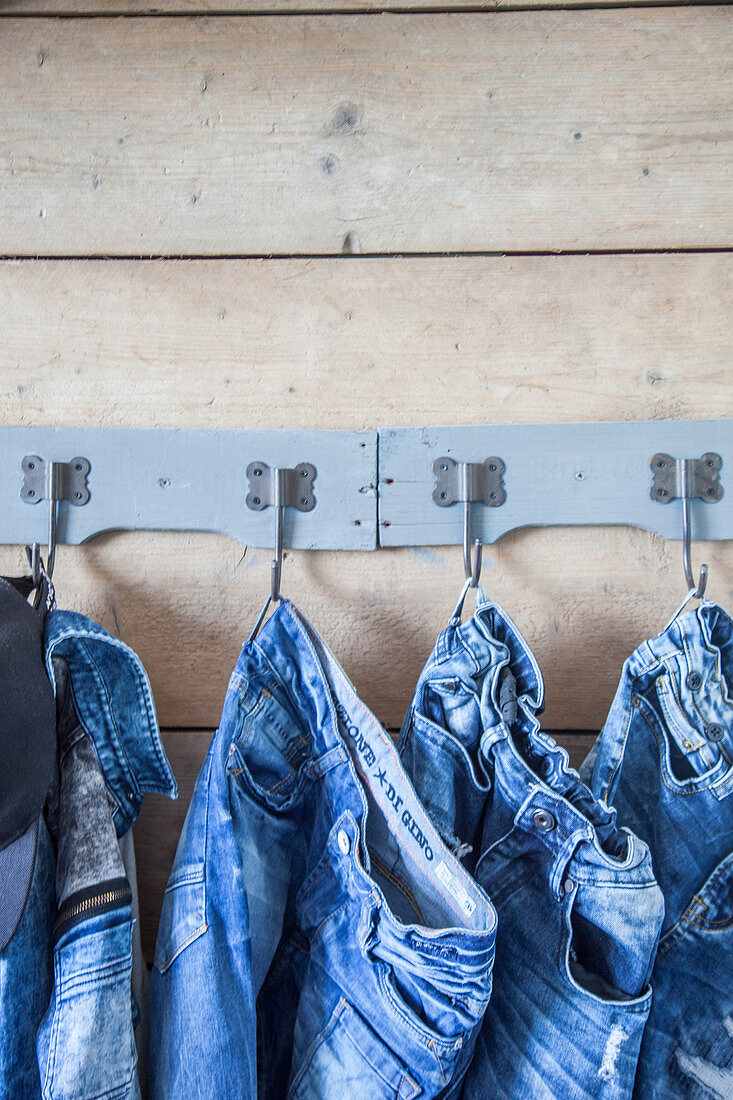 Kleiderstücke aus Jeans an Hakenleiste