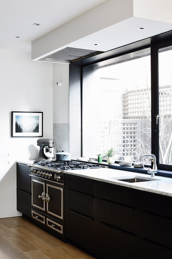 Schwarze Küchenzeile mit Gasherd unter dem Panoramafenster