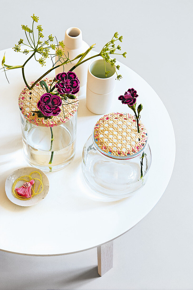 Glass jars with wicker lids as vases