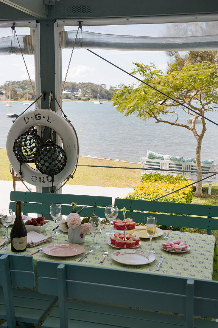 Sommerlich gedeckter Tisch auf der Veranda mit Blick aufs Meer
