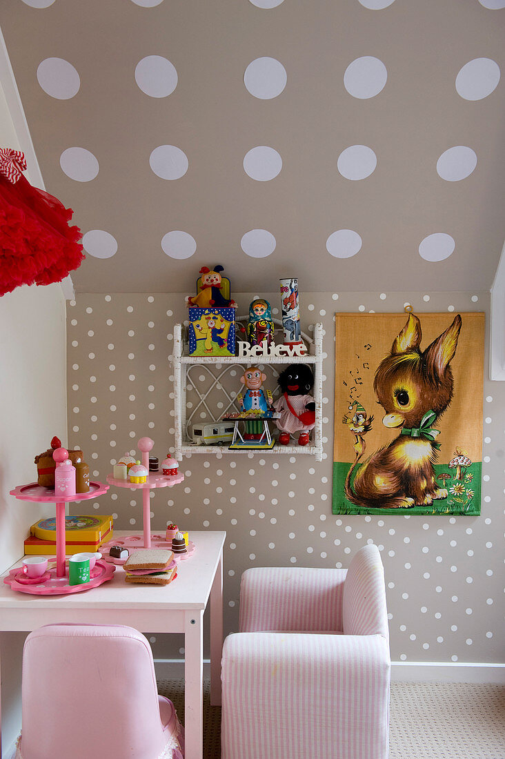 Pink children's furniture next to knee wall with brown-and-white polka-dot wallpaper