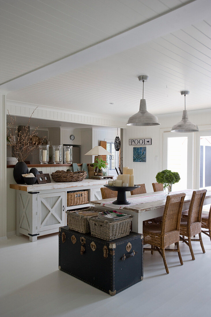 Old trunks at end of dining table in open-plan interior in Hamptons style