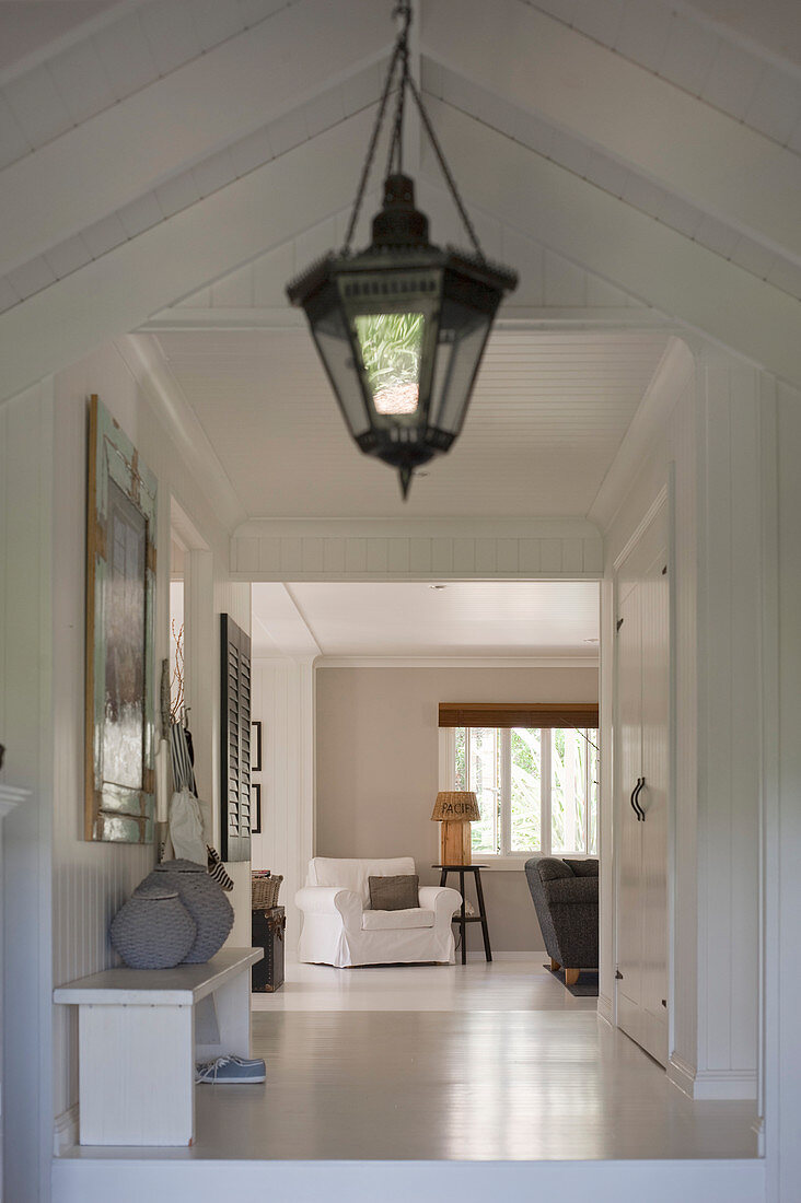 Lantern-style lamp in white, country-house-style hallway with sloping ceiling