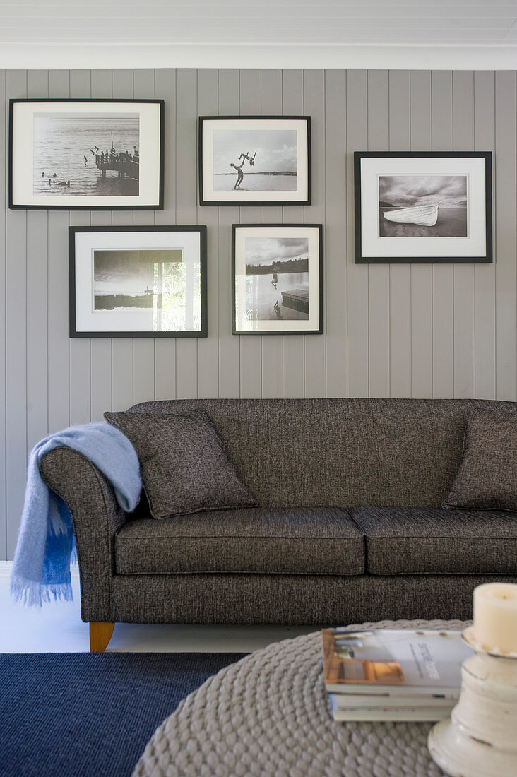 Bildergalerie mit Schwarz-Weiß-Fotos überm grauen Sofa