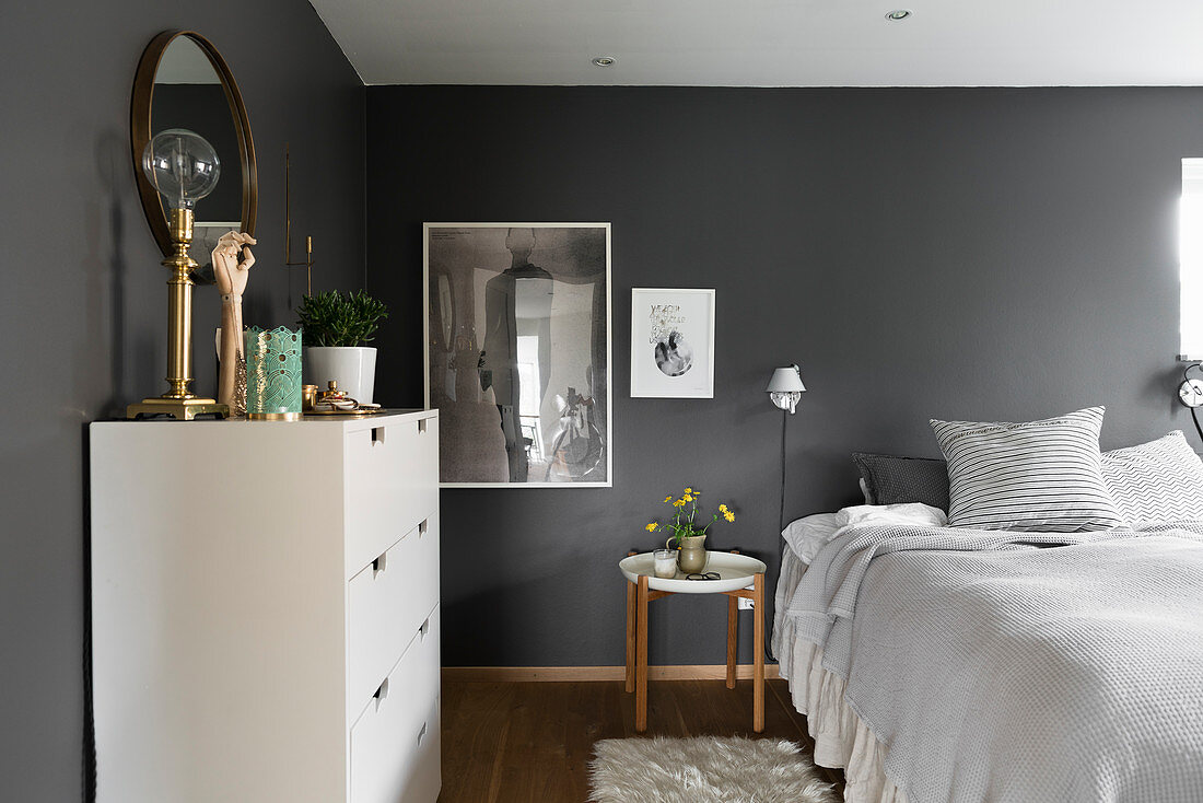Doppelbett und weiße Kommomde im Schlafzimmer mit dunkelgrauen Wänden