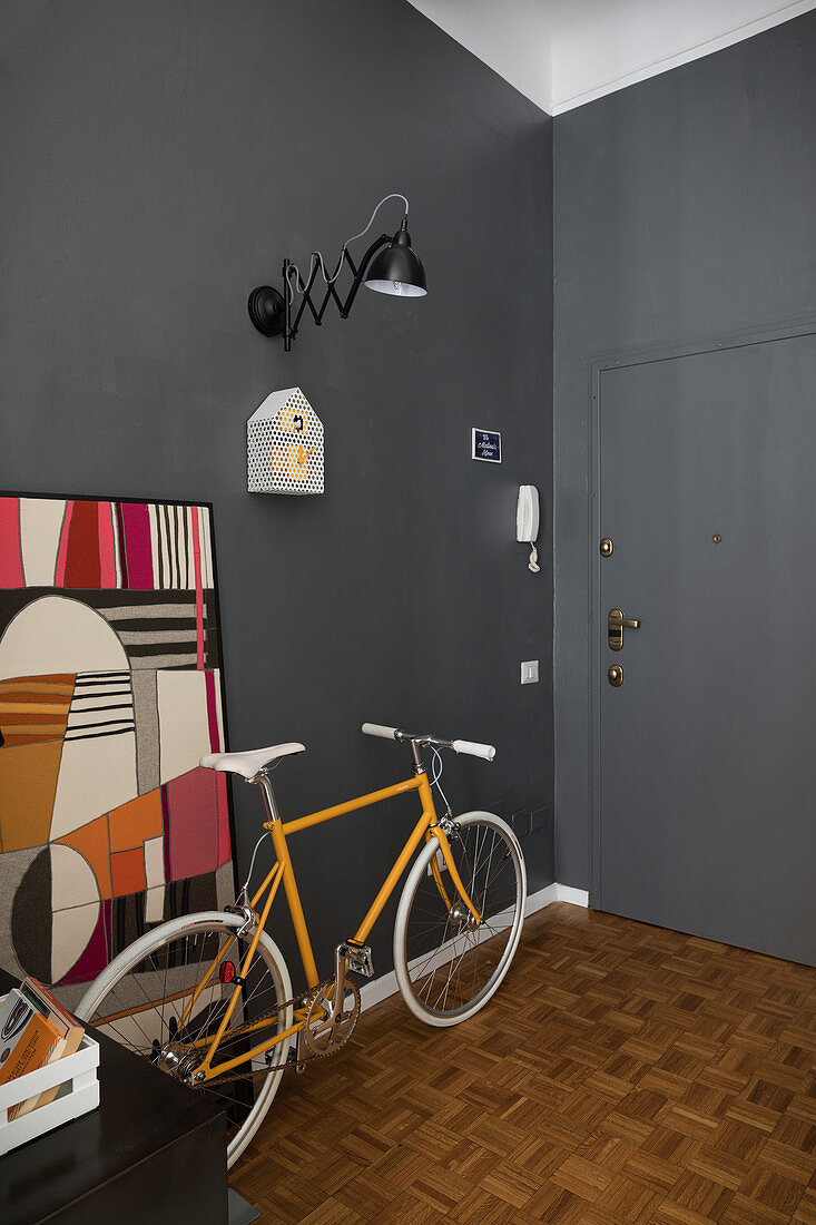Gelbes Fahrrad im Eingangsbereich mit grauen Wänden und grauer Tür