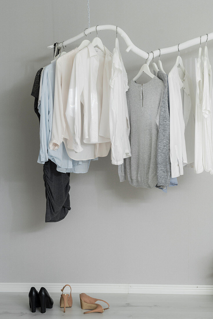 Kleidungsstücke hängen an DIY-Kleiderstange aus weiß gestrichenem Ast