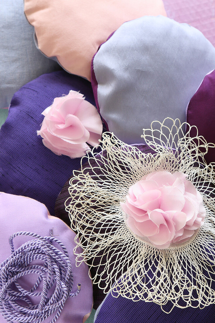 Small round cushions and fabric flowers in various shades of pink and purple
