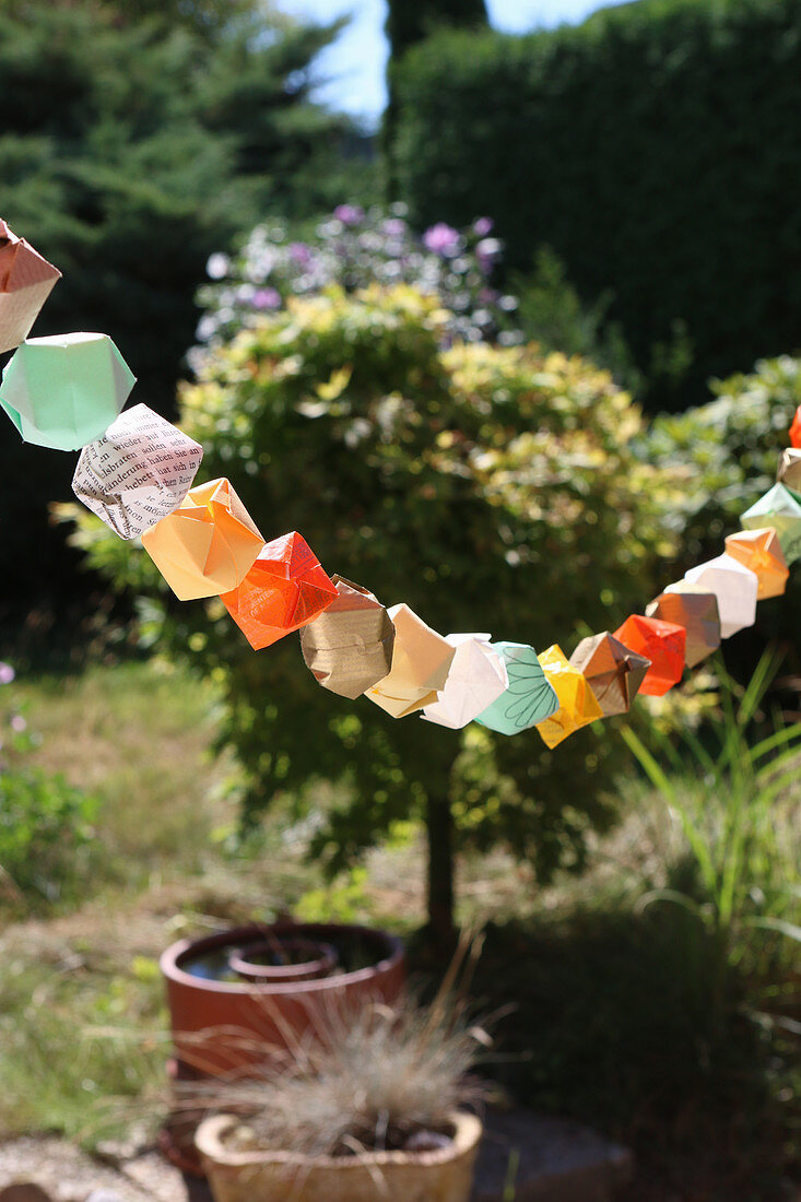 Garland of colourful origami shapes in garden