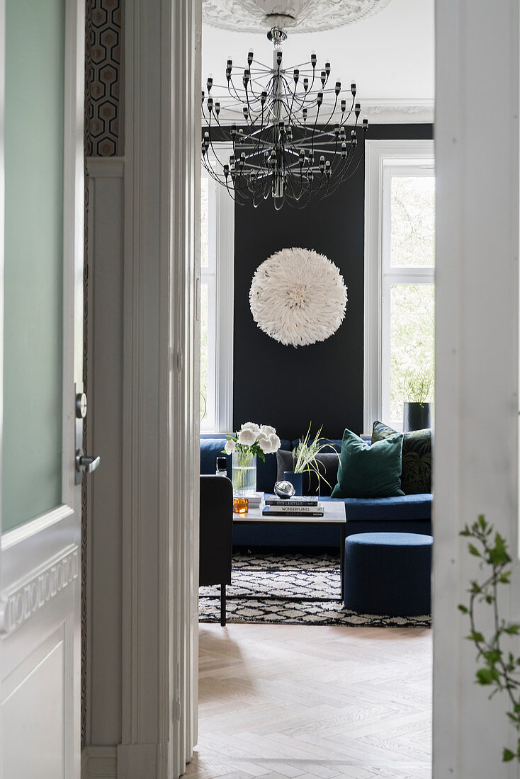 Blick durch geöffnete Tür in elegantes Wohnzimmer mit schwarzer Wand und mit schwarzen und weißen Accessoires