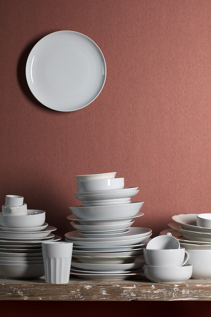 Weisses Geschirr auf Tisch und Teller an Wand dahinter
