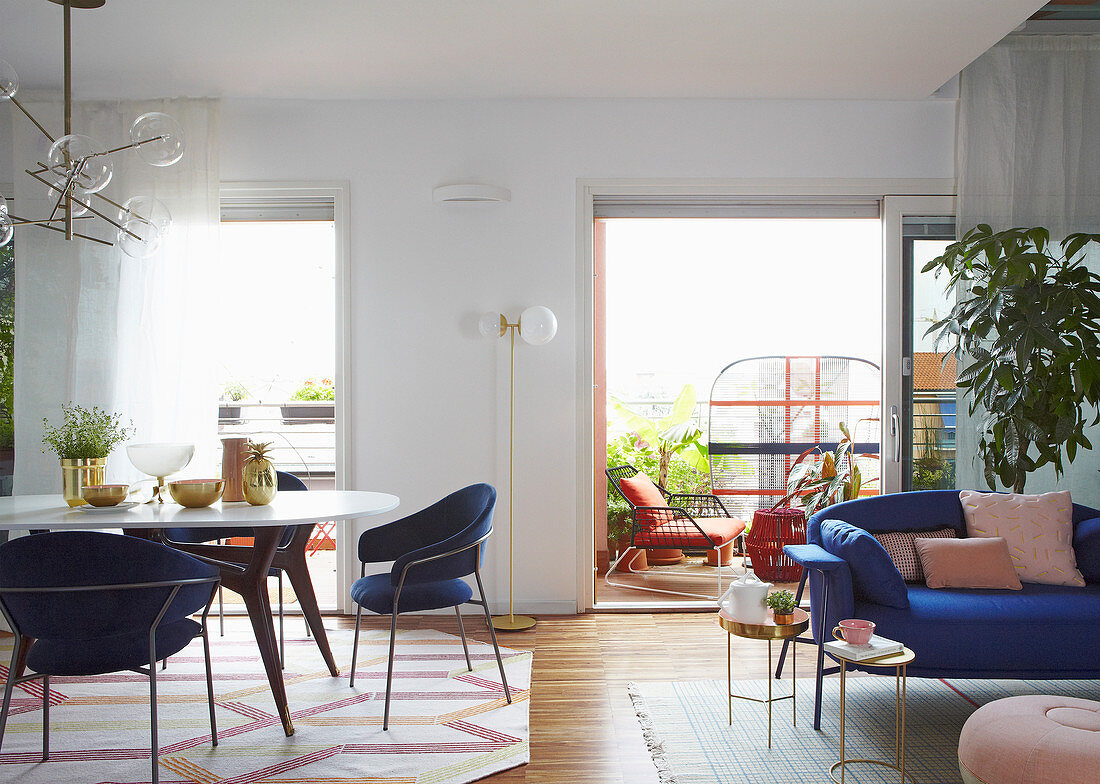 Essbereich mit blauen Armlehnstühlen und Sofa mit Beistelltischen in offenem Wohnraum