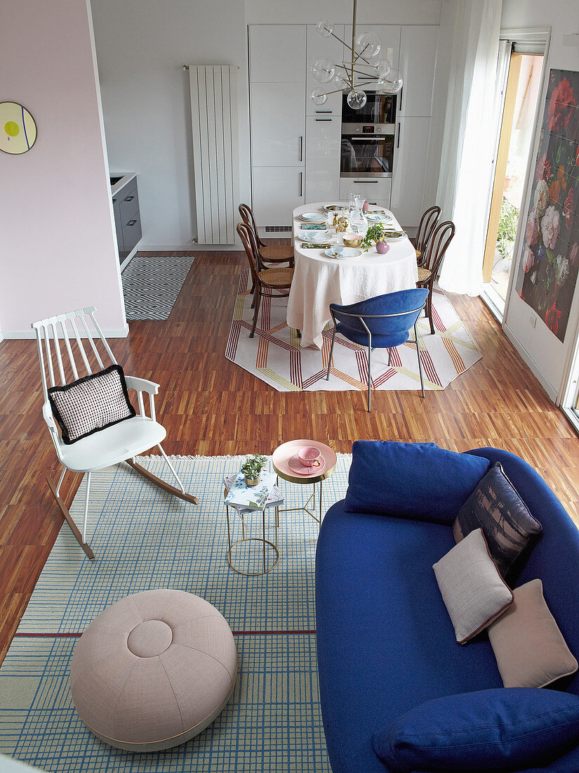 Essbereich mit verschiedenen Stühlen und Sofa mit Beistelltischen in offenem Wohnraum