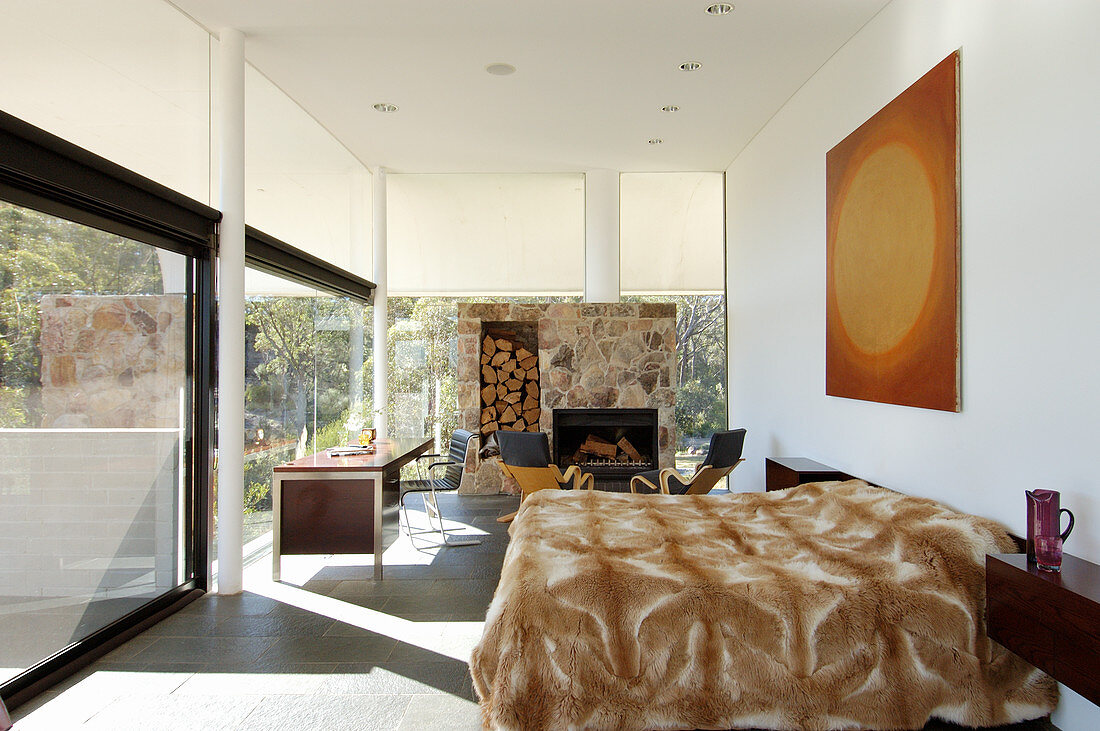 Schlafbereich in offenem Raum mit Kamin und Glasfront