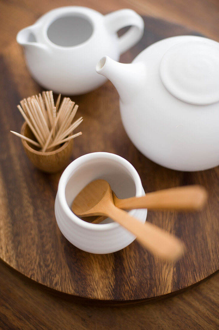 Wooden cutlery, toothpicks and white teapots on wooden table
