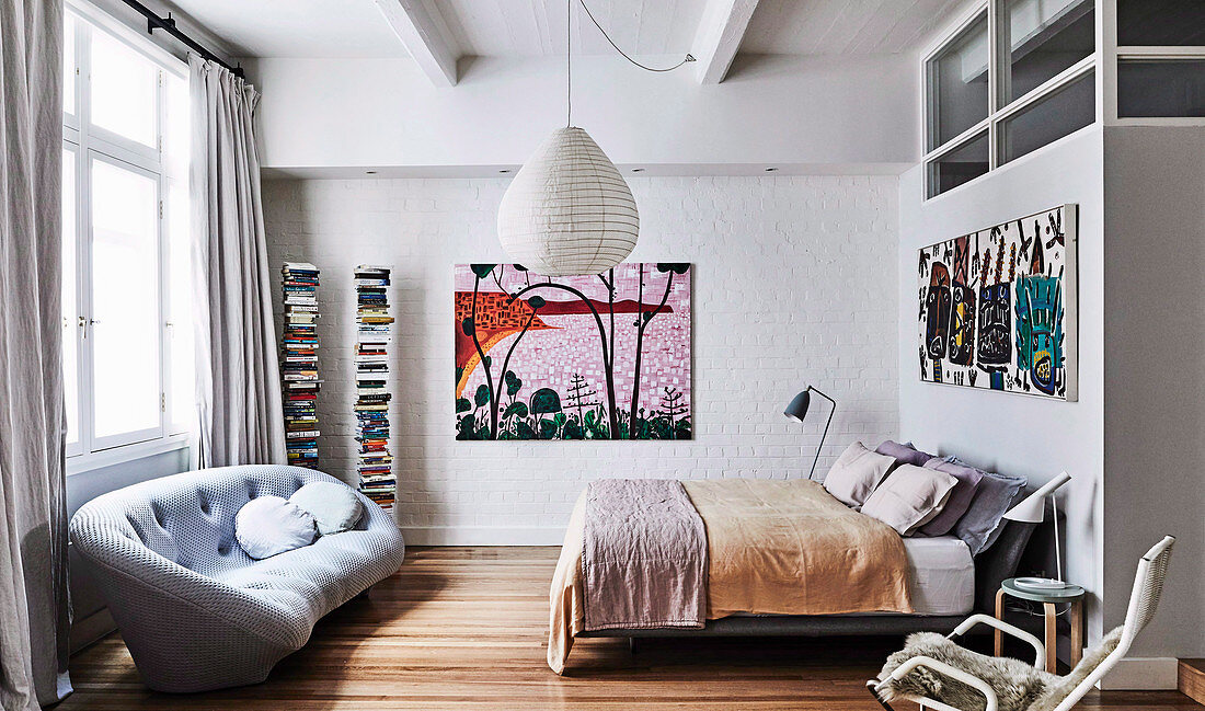 Bedroom with double bed, large-format murals and light gray sofa