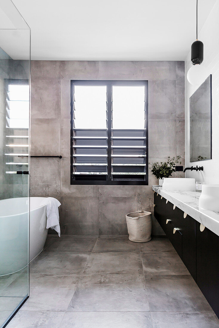 Double vanity, free-standing bathtub and industrial-style tiles in the bathroom