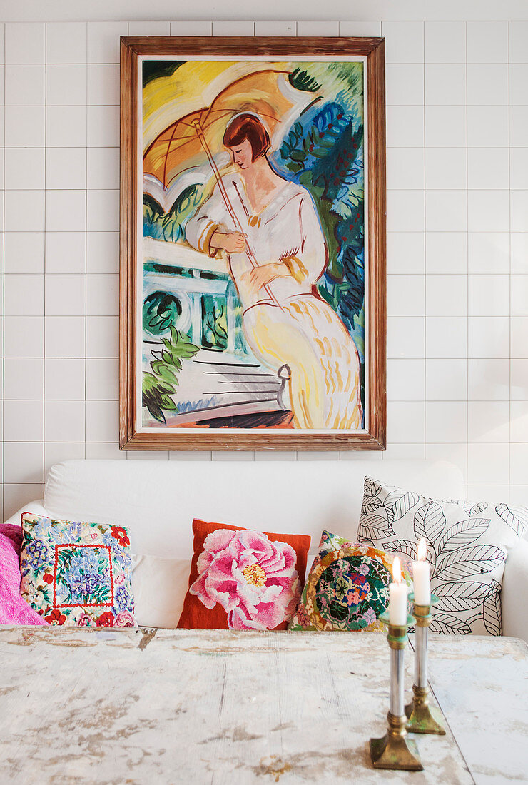 Gemälde über dem Sofa mit bunten Kissen an gefliester Wand