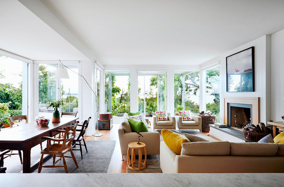 Light-flooded living room of a coastal house with dining area and spacious seating area by the fireplace