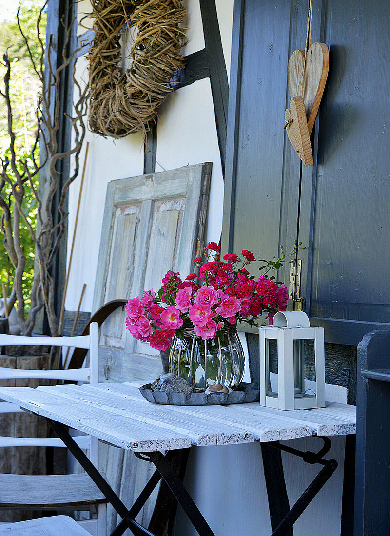 Rosenstrauß in Glasvase auf Gartentisch, Herzen aus Holz