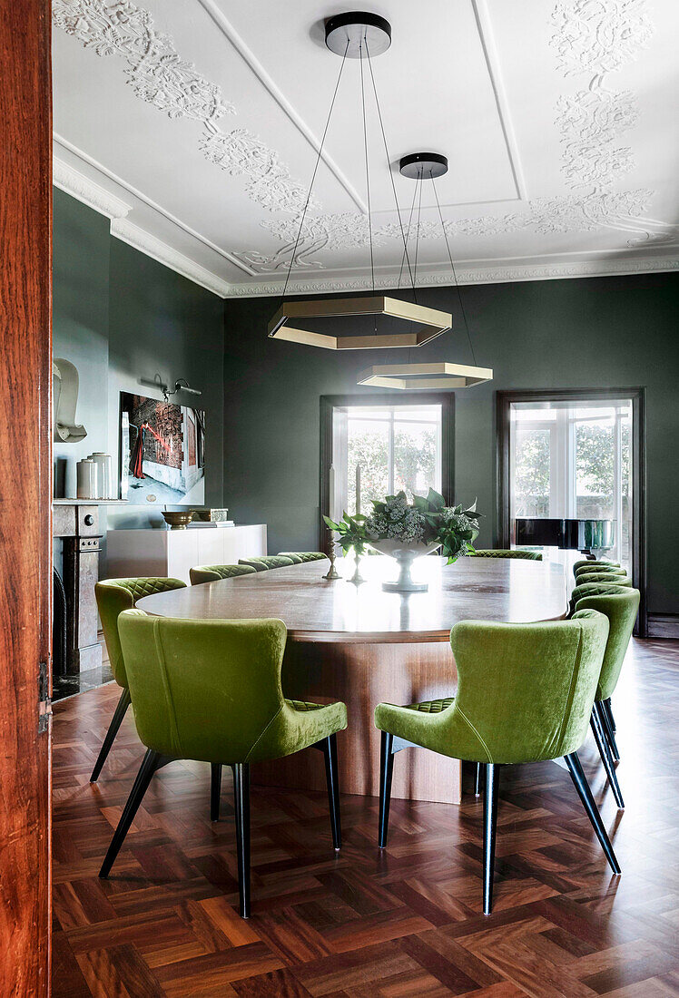 Modern green upholstered chairs around oval chalkboard in parlor with stucco ceiling